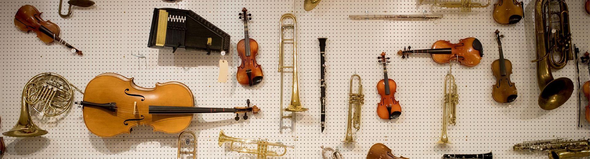 Many different instruments hanging on a pegboard wall.