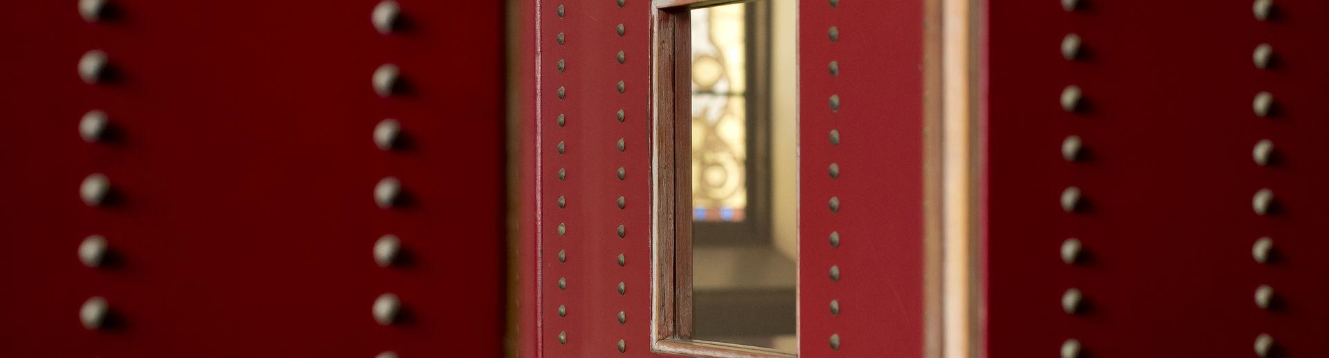 红色镜框内的一面镜子和挂满饰钉的墙壁的特写.
