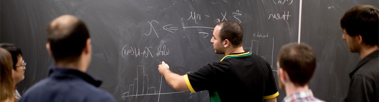 数学教授在黑板上写字，学生们围在一起