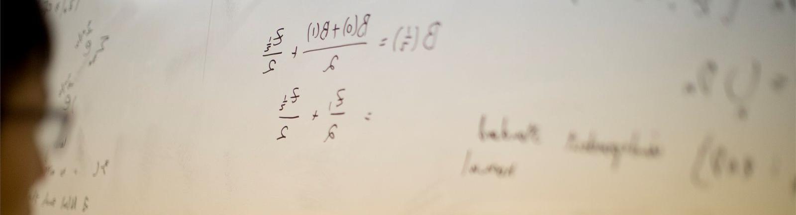 一名学生在科技学院教室的白板上写数学方程式.