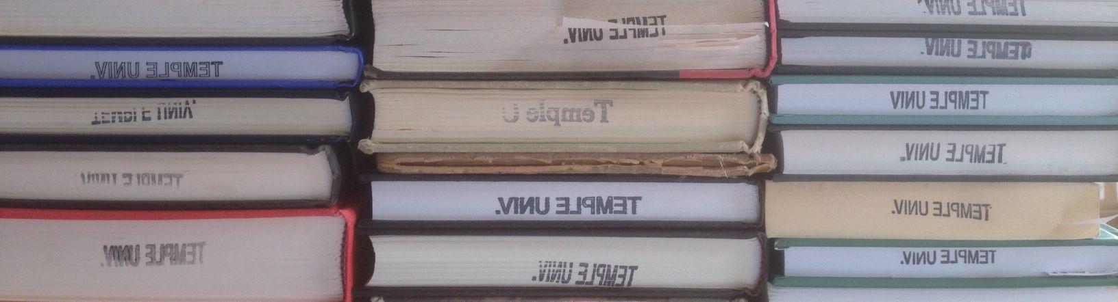 Three stacks of books, each stamped with the words "Temple University."