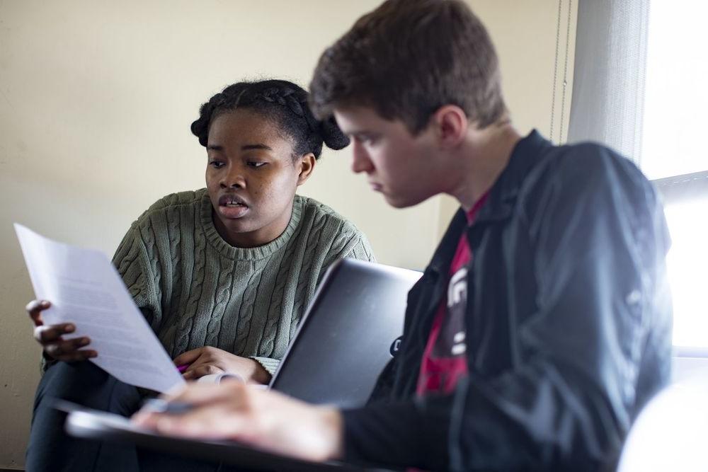 Two students read a paper together.