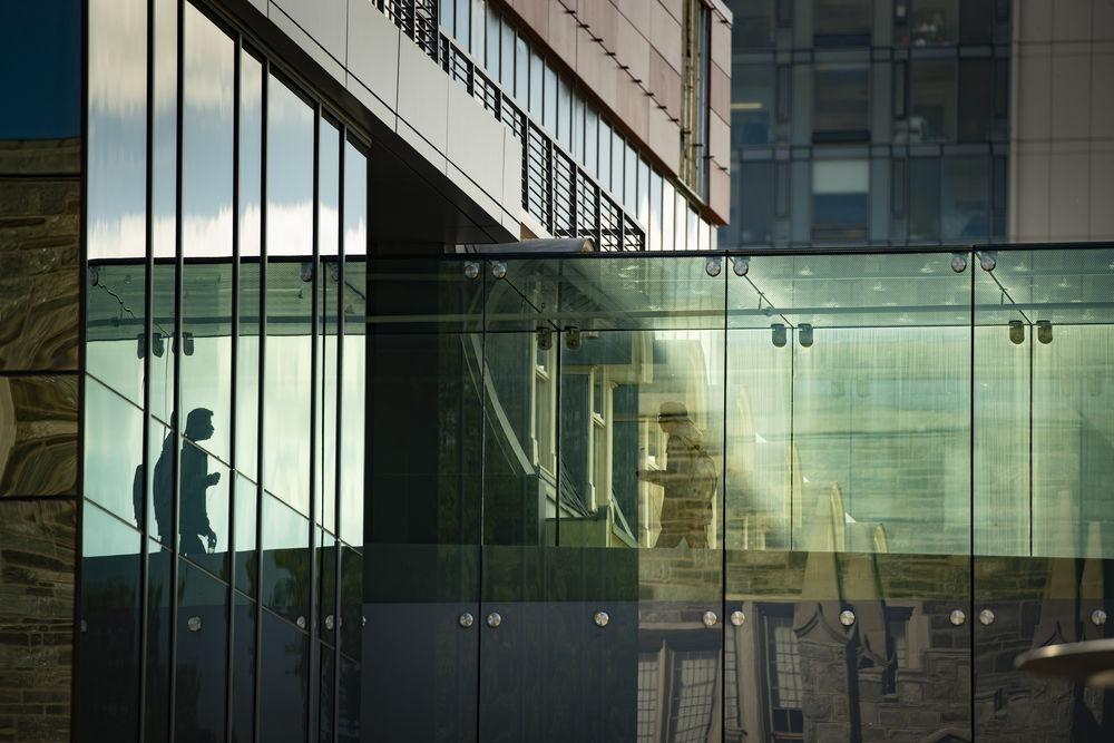 A student walks across the glass bridge between buildings on Temple's main campus.